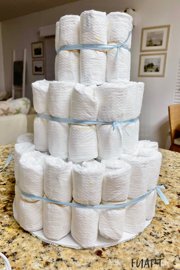 diaper cake | DIY diaper cake | diaper cake tutorial | how to make a diaper cake | gender neutral diaper cake | DIY baby shower gifts | baby shower gift | baby shower gift ideas | baby shower decor | gender neutral baby shower decor | baby boy diaper cake | baby boy shower decor | baby girl shower decor | floral diaper cake | rustic diaper cake | rustic baby shower decor | farmhouse baby shower decor | step by step diaper cake | diaper cake with a bottle of wine inside | wine bottle diaper cake | diaper cake surprise |